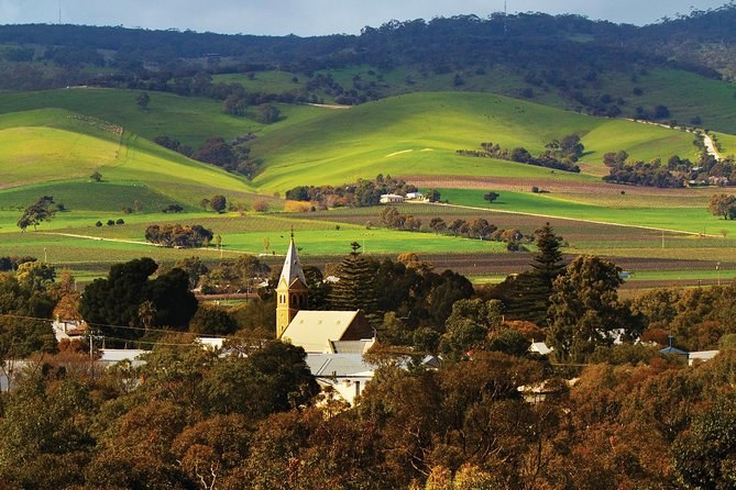 Green hills folding above a village church spire and trees in autumn colour