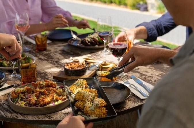 A shared lunch of grilled dishes and glasses of wine on an outdoor table